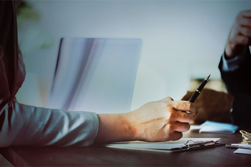 Hand reaching over a desk offering a pen