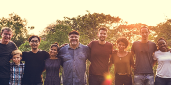 diverse group of adults standing shoulder-to-shoulder outside at sunset