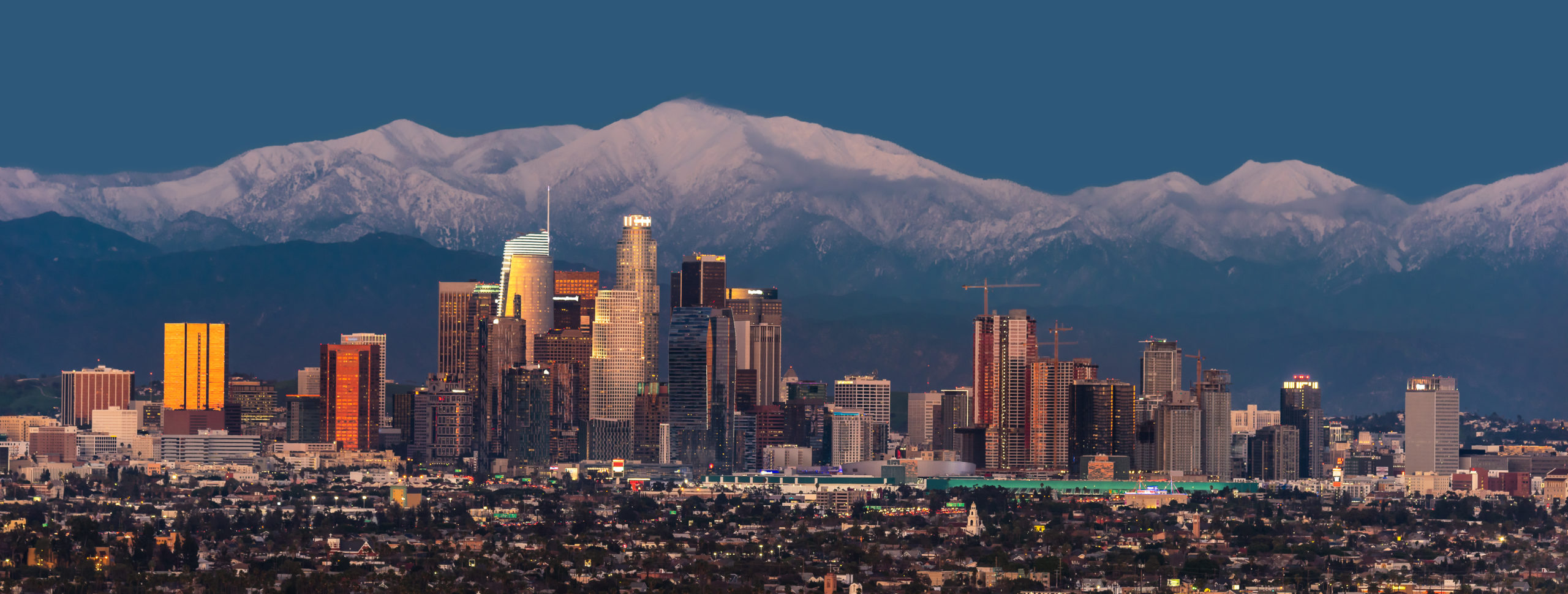 Downtown-Los-Angeles-skyline-with-snow-capped-mountains-behind-at-twilight-scaled