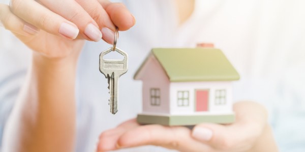 Person holding key and miniature house