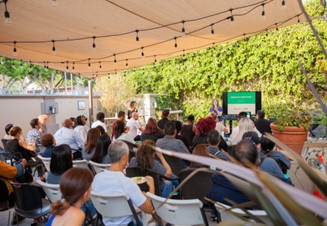 A group of Hollywood residents gathered under an outdoor canopy to watch a presentation.
