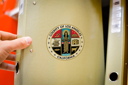 Hand pulling out a department guide binder with the seal of Los Angeles county on it.