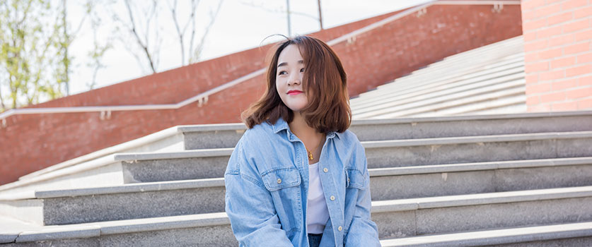 female college student sitting on stairs in front of housing